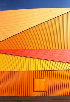 an orange building with red and yellow stripes on it's side against a blue sky