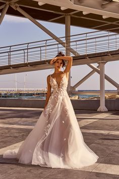 a woman in a wedding dress posing for the camera with her hand on her head