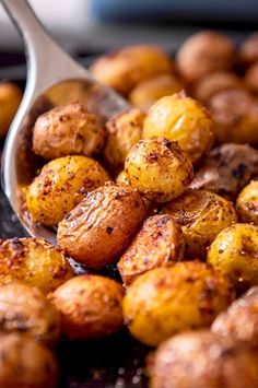 a spoon full of roasted potatoes on top of a table