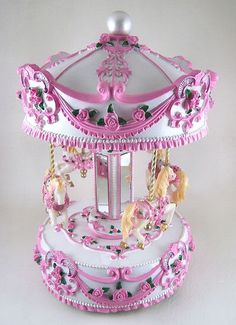 a pink and white carousel with horses on it's sides, sitting against a white background