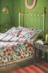 a bedroom with green walls and a floral print bed spread on top of the bed