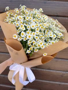 a bouquet of daisies wrapped in brown paper