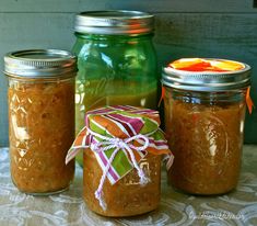 three jars filled with food sitting on top of a table next to an orange and green mason jar