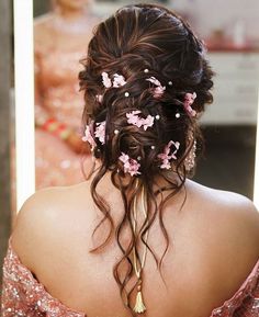 the back of a woman's head with flowers in her hair and pearls on it