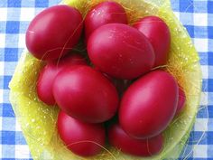 a bowl filled with red eggs on top of a blue and white checkered table cloth