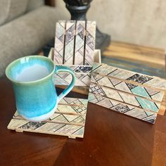 a blue cup sitting on top of a wooden table next to coasters