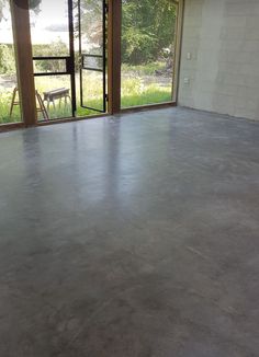 an empty room with concrete floors and large windows