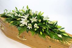 a wooden casket filled with white flowers and greenery on top of it's sides