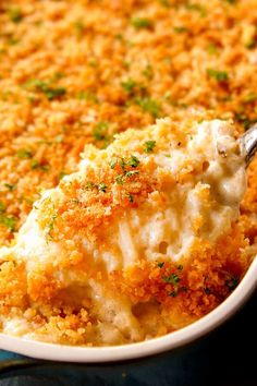 a spoon in a casserole dish with cheese and parsley