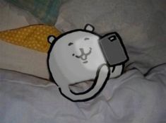 a polar bear holding a cell phone in it's mouth while laying on a bed