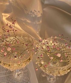 two clear wine glasses with pink flowers in them