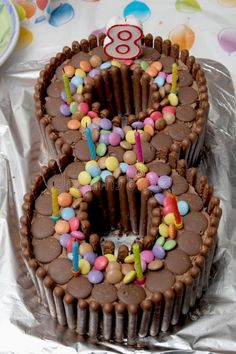 two chocolate birthday cakes with candles in the shape of number eight on tin foil stock photo