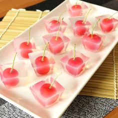 small cherries are arranged on a plate with toothpicks in the shape of hearts