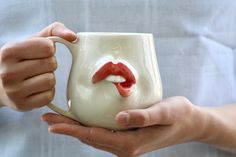 a person holding a coffee mug with a red lip painted on it