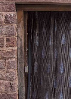 a cat sitting in the window sill of a brick building with blue and white curtains