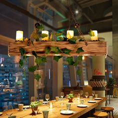 a wooden table topped with lots of plates and glasses next to a window filled with tall buildings