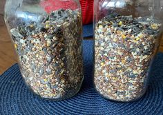 two glass jars filled with bird seed on top of a blue mat