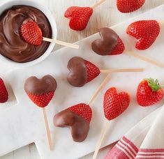 chocolate covered strawberries on skewers next to a small bowl of melted chocolate