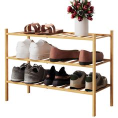 four pairs of shoes are on a wooden shelf next to a vase with flowers in it