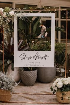 a sign that is sitting in front of some potted plants and other flowers on a table