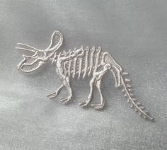 the skeleton of a dinosaur is shown in frosted glass on a silver surface with snow flakes around it