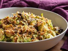 a white bowl filled with broccoli covered in cheese and crumbled on top