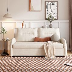 a living room with a white couch and some pictures on the wall above it's headboard