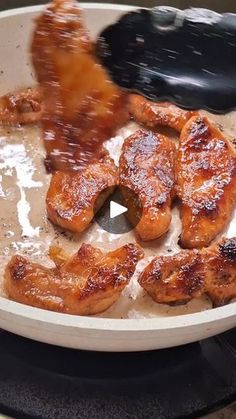 chicken wings being cooked in a skillet with sauce and seasoning sprinkles