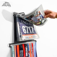 Finally, an all-in-one display for your race bibs and race medals that is sure to WOW. Our Race Medal & Bib Display turns your race bibs and medals into a work of art on your wall. Easily slide your medals onto the lower bar of the hanger and your race bibs easily hook onto the upper portion of the display. Can hold up to 24 medals and over 100 bibs. *We also recommend additional BIB PROTECTOR INSERTS for your BibFOLIO (sold separately in sets of 12): These custom BibFOLIO race bib sleeves, made Race Bib Display Diy, Running Bib Display, Race Bib Display, Race Medal Holder, Hanging Medals, Race Bib Holder, Race Medal Displays, Sports Medal Display, Running Bibs