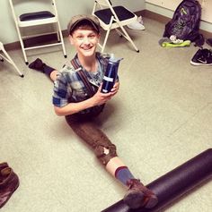 a young boy sitting on the floor holding a skateboard in his hands and smiling