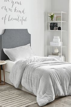 a bed with white sheets and pillows in a bedroom next to a book shelf filled with books