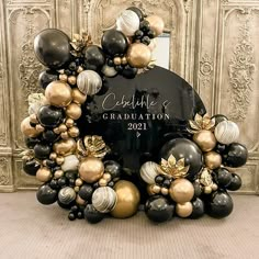 a black and gold graduation balloon arch with balloons in the shape of wreaths on it