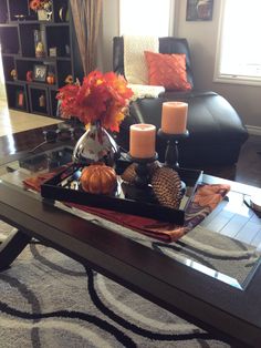 a coffee table with candles, flowers and pumpkins on it in a living room