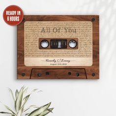 an old fashioned audio cassette with the words all of you printed on it, next to a potted plant