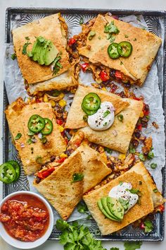 mexican food on a tray with sauces and guacamole