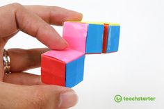 a hand is holding a small toy block