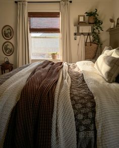 a bed sitting under a window in a bedroom next to a wall mounted shelf with pictures on it