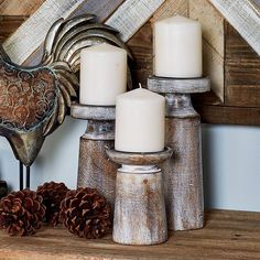 some candles are sitting on a shelf with pine cones