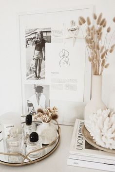 a table topped with vases filled with flowers next to books and other items on top of it