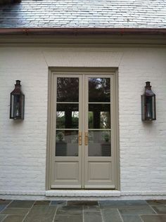 an exterior color scheme for a house with white brick walls and doors, two lanterns on either side of the door