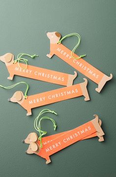 four wooden dachshunds with merry christmas tags hanging from the strings on a green surface