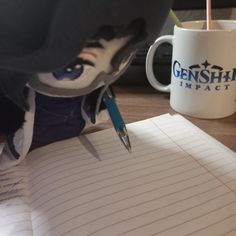 a person writing on lined paper next to a coffee mug