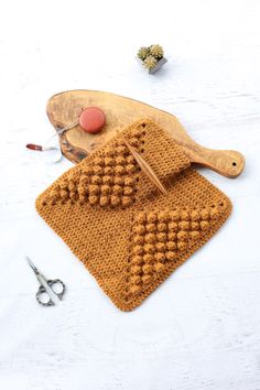 a crocheted dishcloth and pair of scissors on a white surface