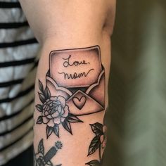 a woman with a tattoo on her arm that says i love mom and has flowers around it