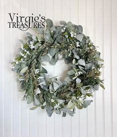 a wreath with white flowers and greenery hanging on the wall next to a sign that reads, virgo's treasures