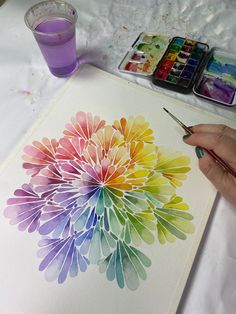 someone is painting a flower with watercolors on paper