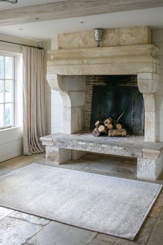 a living room with a fire place and rug in front of the fireplace that has logs on it