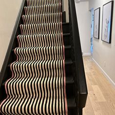 the stairs are lined with black and white striped carpet, along with pictures on the wall