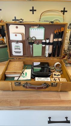 an open briefcase filled with office supplies on top of a wooden table next to other items