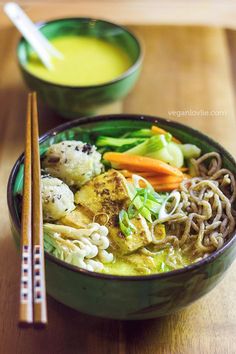 a bowl filled with noodles and vegetables next to chopsticks